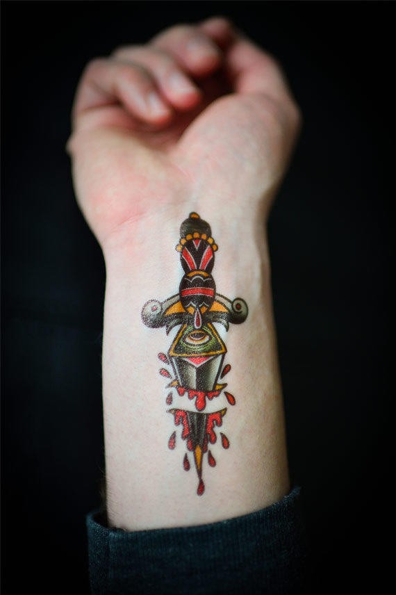 Old school style colored wrist tattoo of bloody fantasy dagger