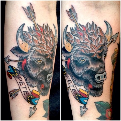 Old school style designed bulls head forearm tattoo stylized with arrows and lettering