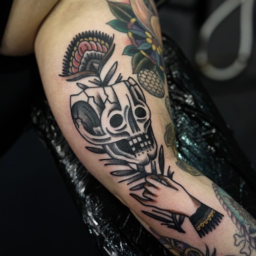 vecchia scuola stile progettato cranio con fiore in mano tatuaggio su braccio