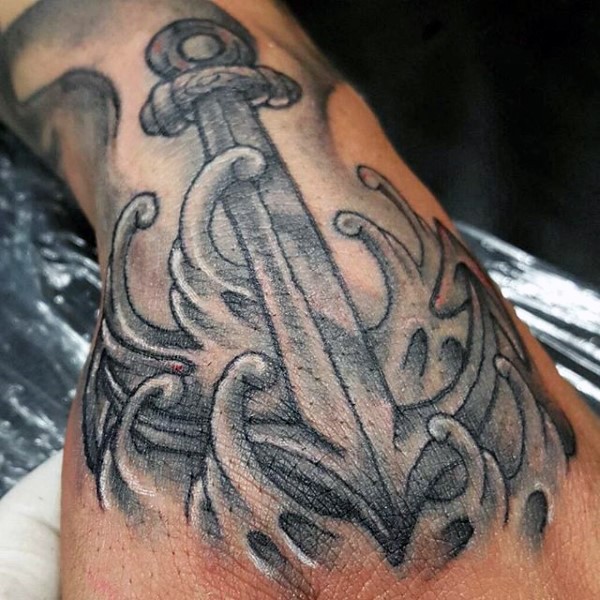 Old school style painted black and white anchor in waves tattoo on wrist