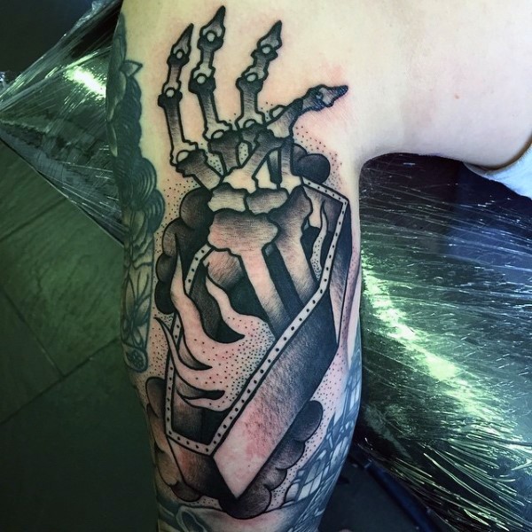 Tatuaje en el brazo, mano esqueletico en ataúd, estilo old school