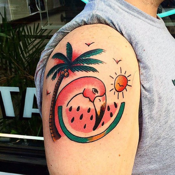 Old school style painted flamingo with palm tree tattoo on upper arm
