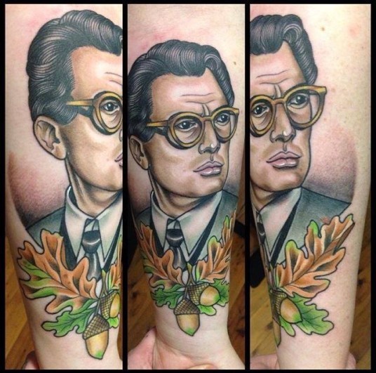 Tatuaje en el antebrazo, retrato de hombre en gafas con hojas de roble