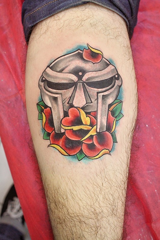 Old style colored antic warriors helmet tattoo on leg stylized with flower