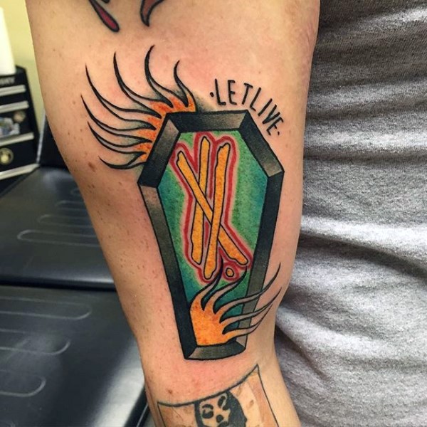 Old style colored coffin with crossed lines and fire flames arm tattoo with lettering