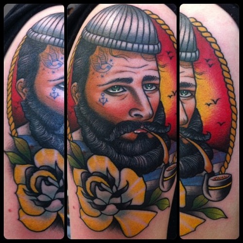 Old style colored smoking sailor portrait tattoo on shoulder stylized with flower