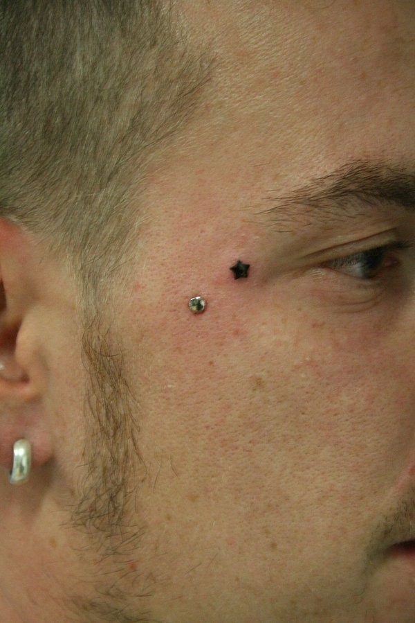 Tatuaje de estrella negra diminuta en la cara