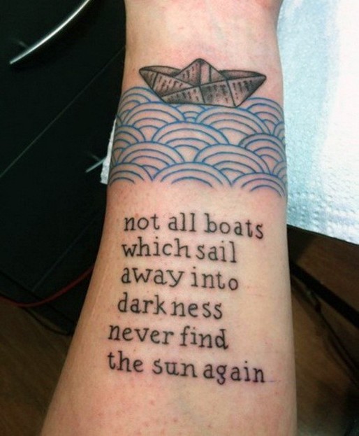 Original painted black ink paper ship with lettering tattoo on wrist