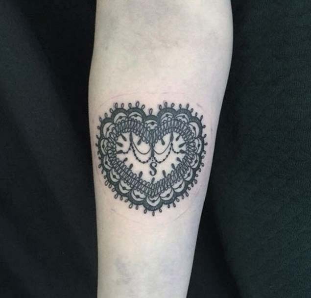 Ornamentaler Stil schwarzes und weißes herzförmiges Tattoo am Unterarm