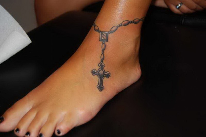 Tatuaje de cruz religiosa en el tobillo