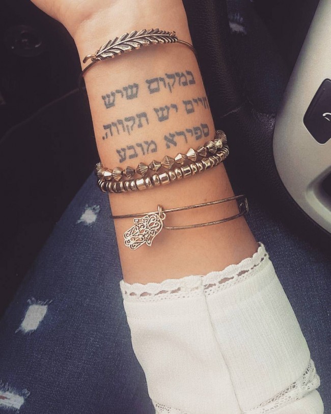 Pale black ink Arabic lettering tattoo on lady&quots wrist
