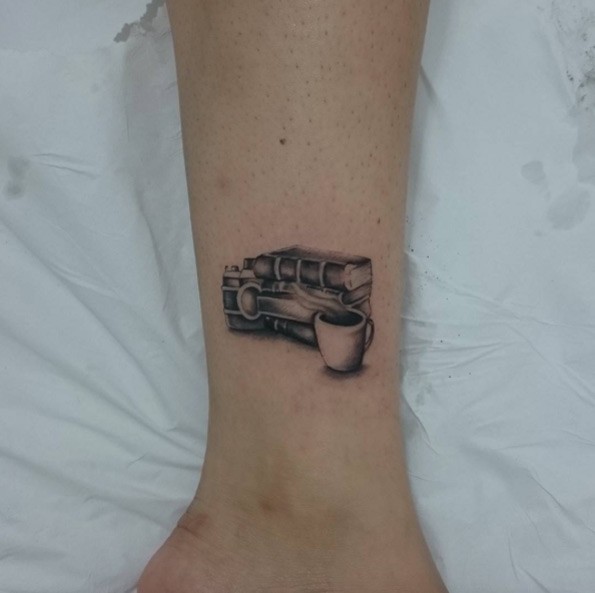 Pale of book and steaming tea cup small size ankle tattoo