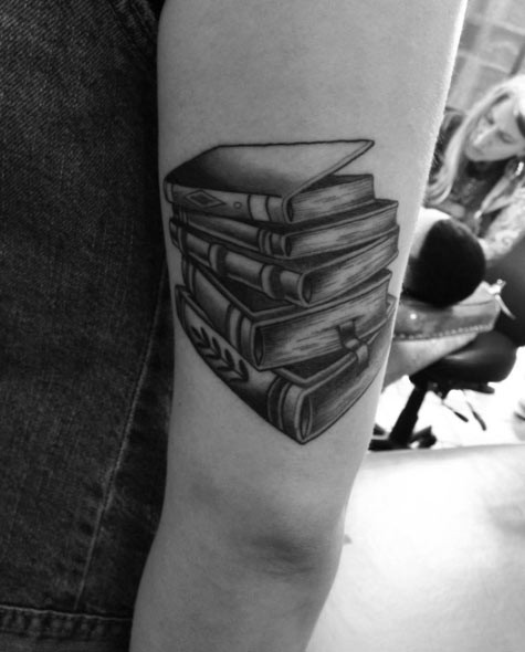 Pale of books with bookmarks tattoo near elbow