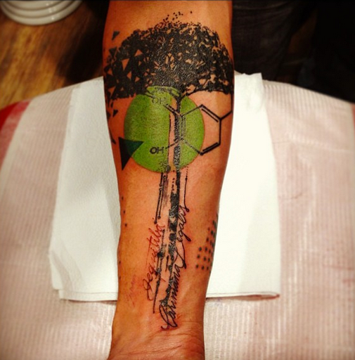 Photoshop style colored forearm tattoo of big tree with lettering and ornaments