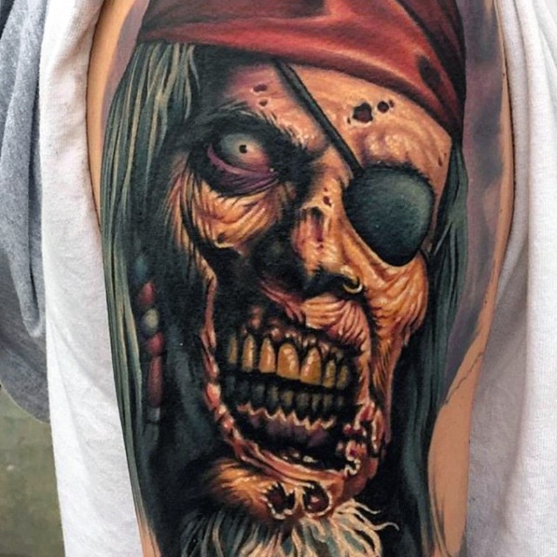 Pirate cartoon themed detailed and colored old zombie portrait tattoo on upper arm