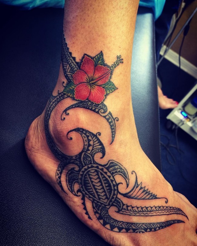 Polynesian tribal style swimming turtle tattoo and colored Hibiscus flower on foot and ankle
