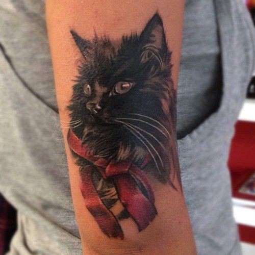 Tatuaje en el brazo, gato negro con lazo rojo