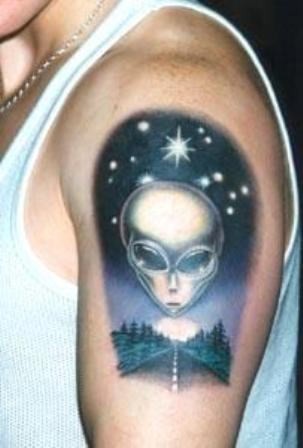 Tatuaje en el brazo,
rostro de criatura extraterrestre  y camino