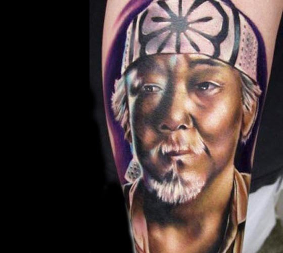 Portrait style colored arm tattoo of Asian man face