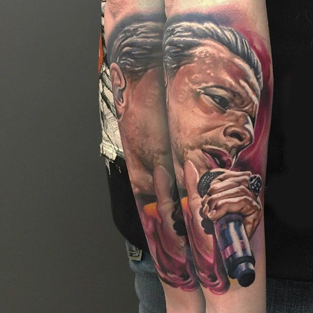 Portrait style colored arm tattoo of famous singer face