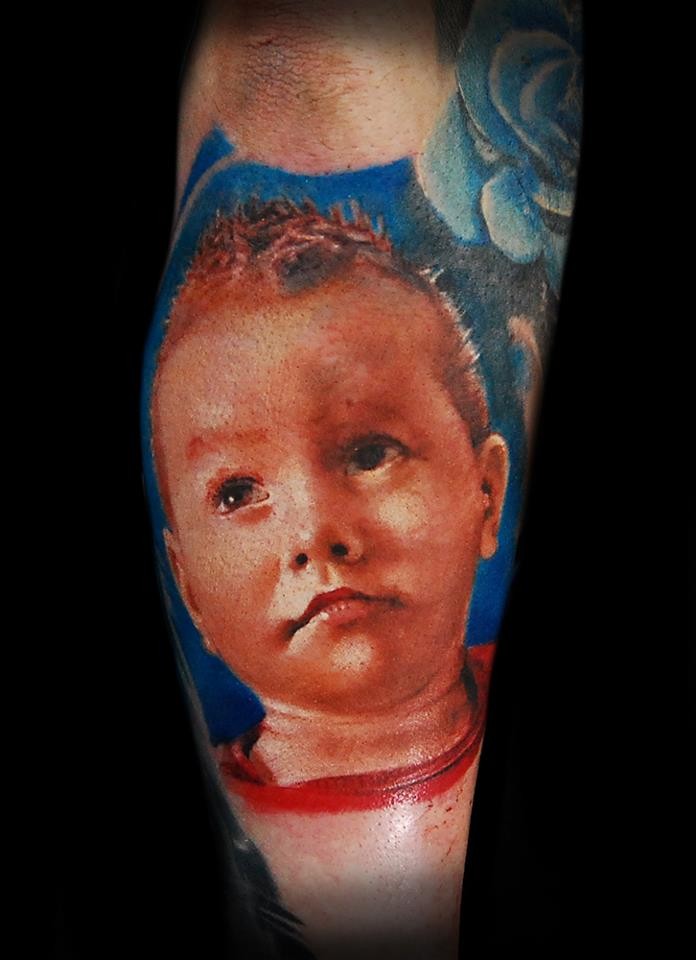 Portrait style colored arm tattoo of little boy