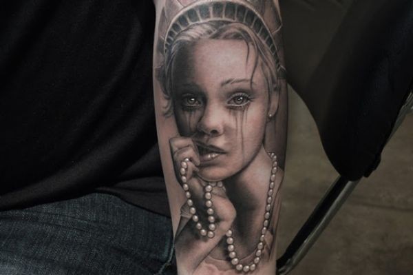 Portrait style colored crying woman face tattoo on arm