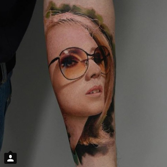 Portrait style colored forearm tattoo of woman with sunglasses