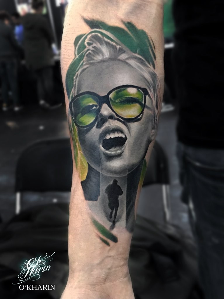 Portrait style colored forearm tattoo of woman with glasses