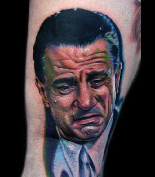 Portrait style colored leg tattoo of Robert DeNiro face