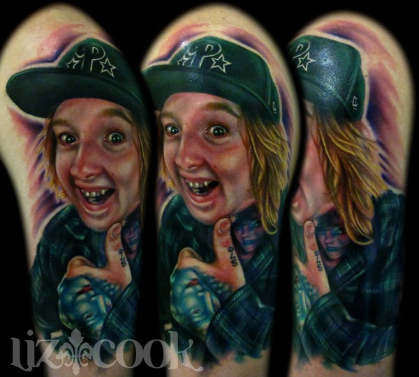 Portrait style colored shoulder tattoo of smiling boy