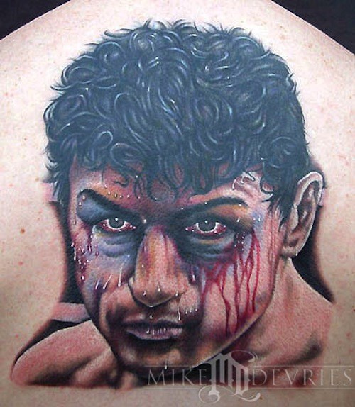 Portrait style natural looking colored upper back tattoo of bloody boxers face