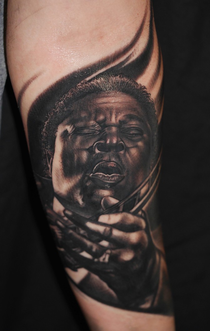 Portrait style realistic looking detailed forearm tattoo of famous guitar player