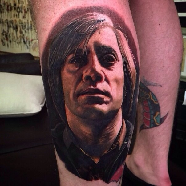 Portrait style very detailed and colored leg tattoo of 007 villain face