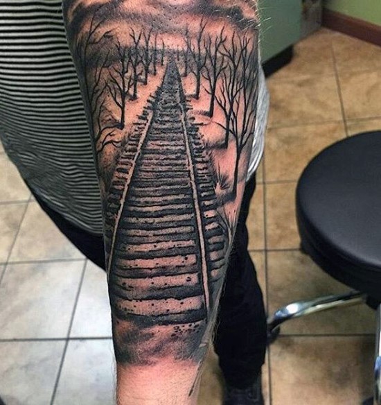 Railway in forest detailed realistic tattoo on arm