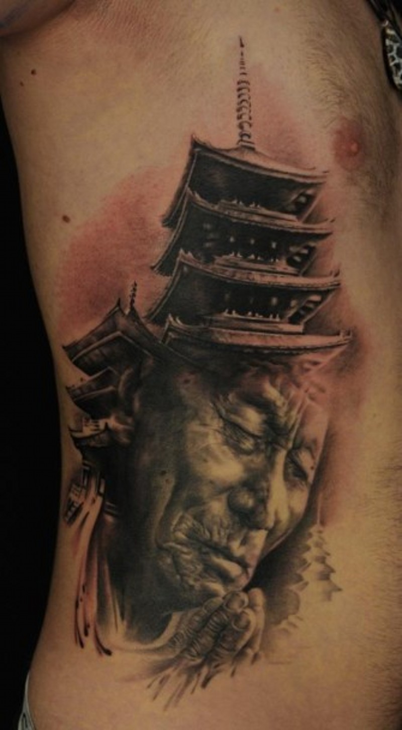 Real life style detailed praying old Asian monk tattoo on side combined with big temple