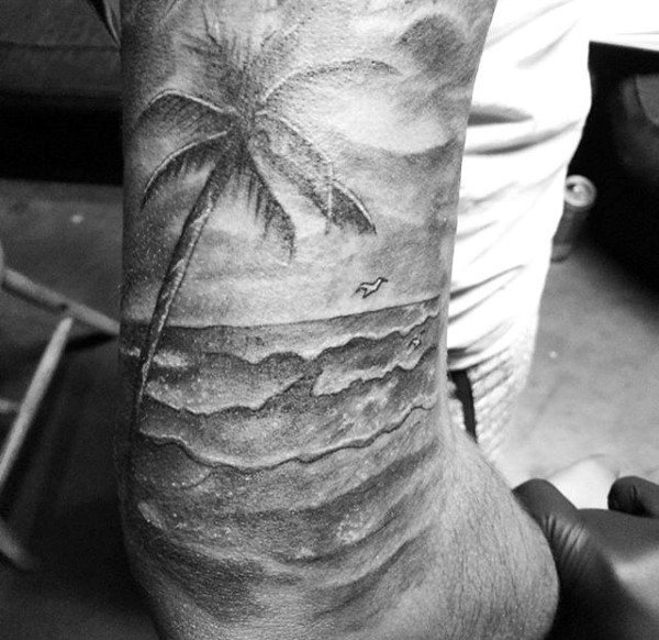 Tatuaje en el hombro, palmera con gaviota y mar, colores negro blanco