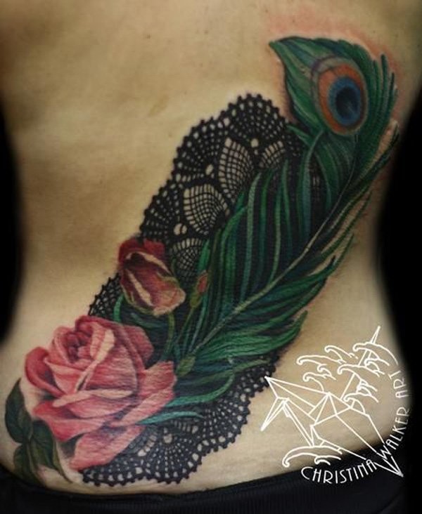 Realism style amazing looking colored back tattoo of rose flower with peacock feather