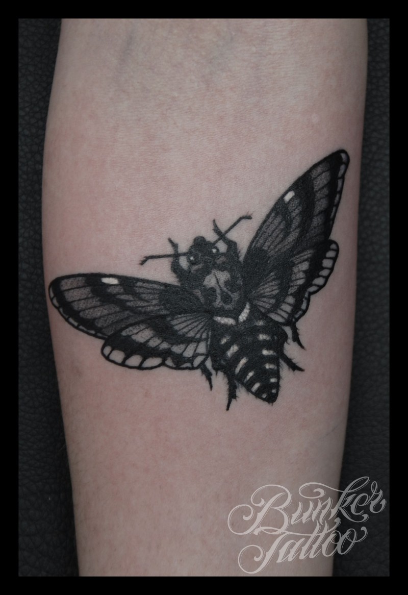 Realism style black ink arm tattoo of butterfly stylized with human skull