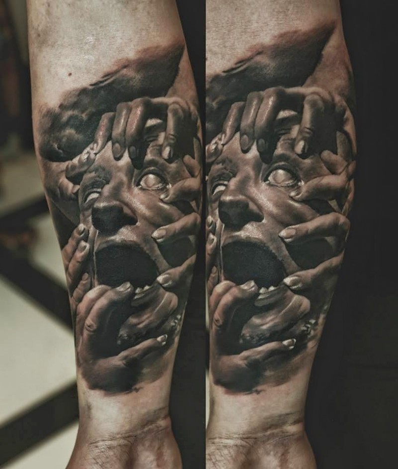 Realism style colored arm tattoo of screaming human face with hands