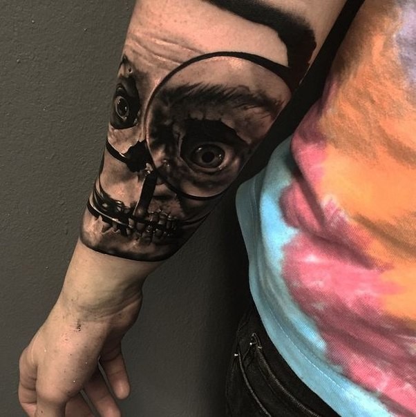 Realism style colored arm tattoo of creepy skull with loupe
