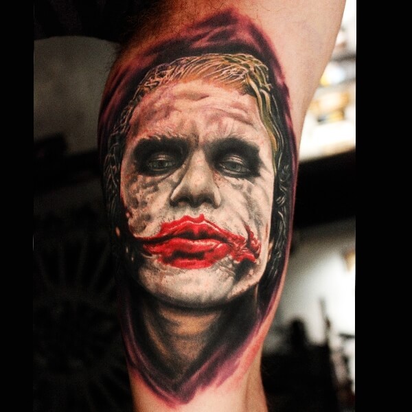 Realism style colored biceps tattoo of evil Joker