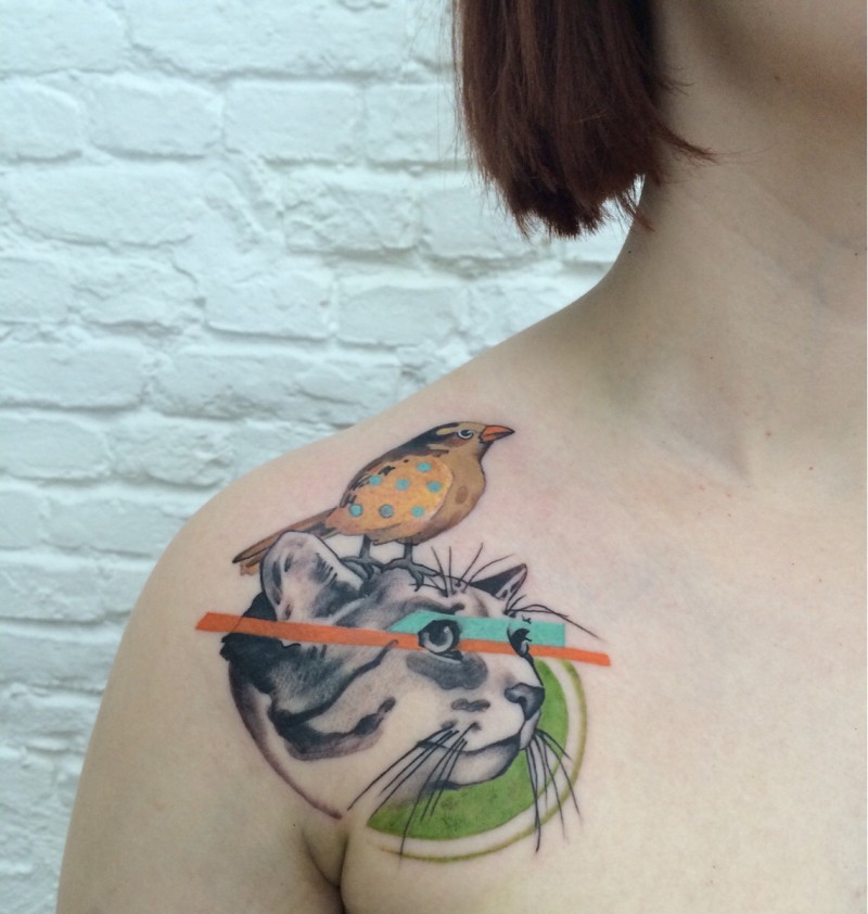 Realism style colored cat face with little bird tattoo on shoulder