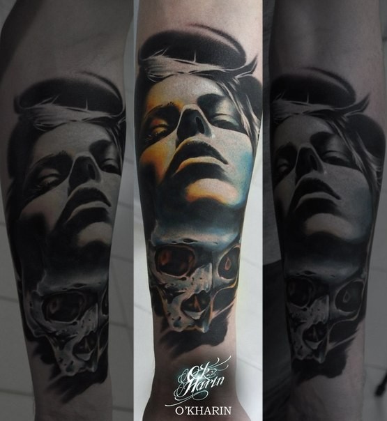 Realism style colored forearm tattoo of human face with skull