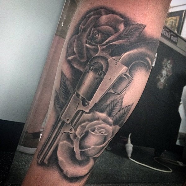 Realism style colored leg tattoo of old revolver with rose flowers