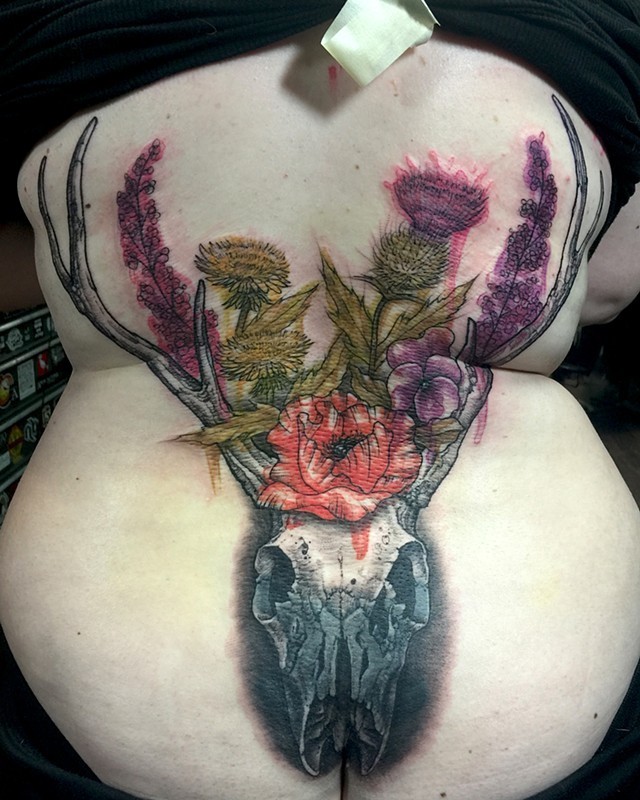 Realism style large colored back tattoo of deer skull and wildflowers