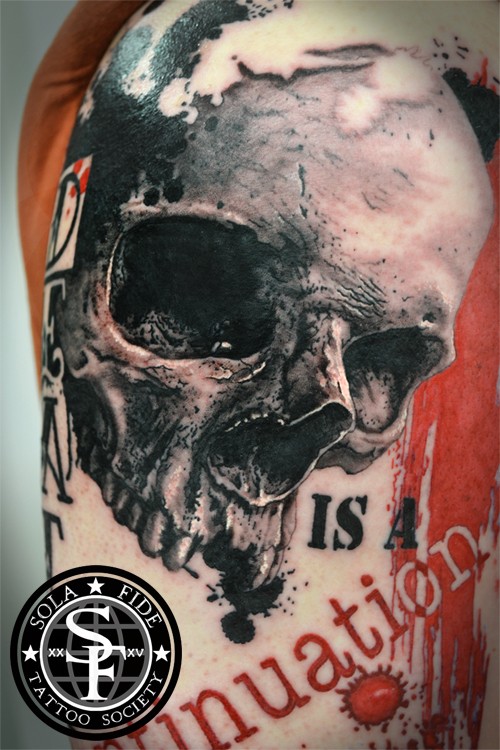 Realism style very detailed tattoo of large skull and lettering