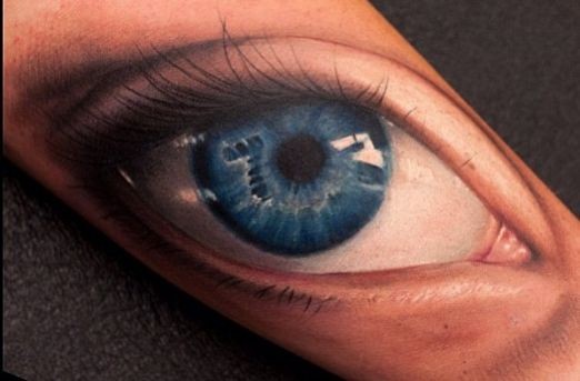 Tattoo mit realistischem blauem Auge am Arm