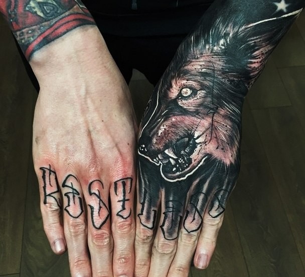 Realistischer wütender dunkler Wolf Tattoo auf der Hand mit Schriftzug auf den Fingern