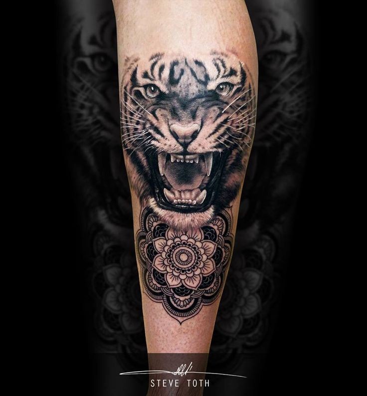 Realistic looking black ink tattoo of roaring tiger with ornamental flower