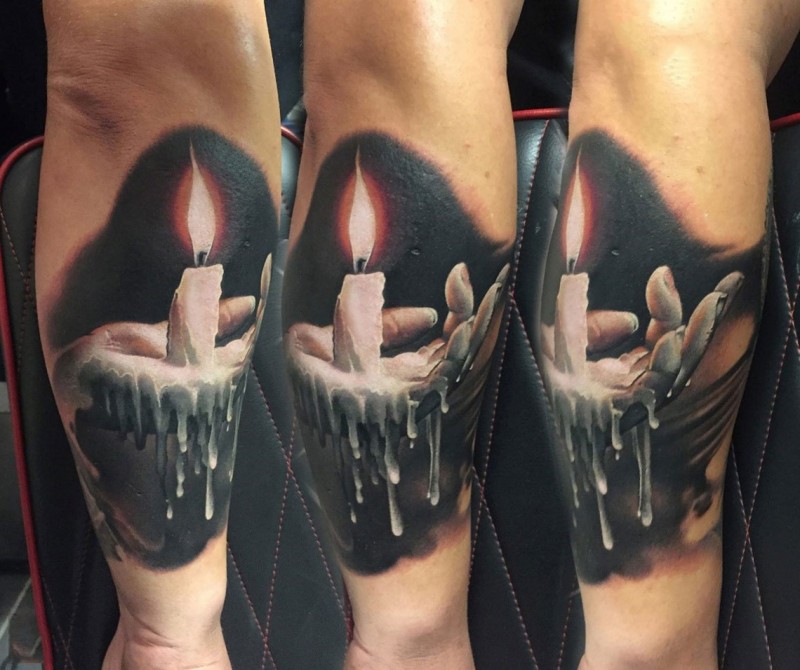 Realistic looking colored arm tattoo of hand holding candle